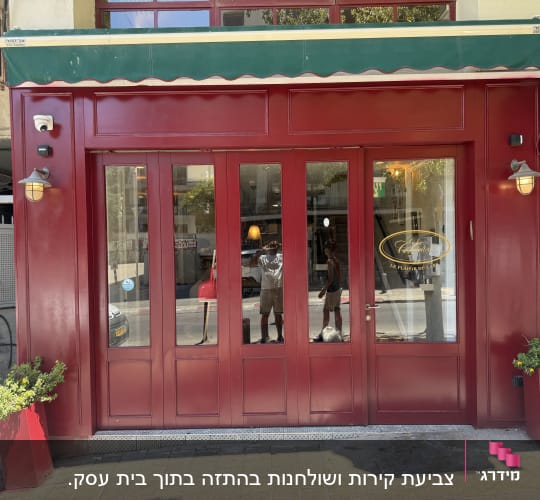 חזית חנות עם דלתות אדומות וצמחים בעציצים